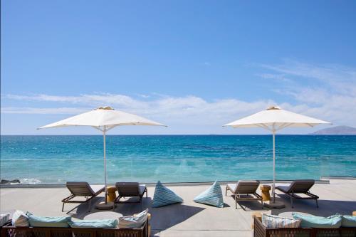 马斯蒂查里Ammos Luxury Resort的海滩上的一组椅子和遮阳伞