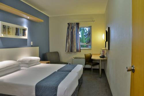 开普敦Road lodge Hotel Cape Town International Airport -Booked Easy的酒店客房设有一张大床和一张书桌。