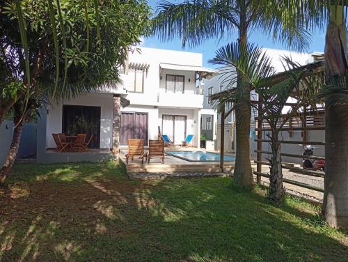 特鲁欧克比赫斯Villa Coco的白色的房子,设有游泳池和棕榈树