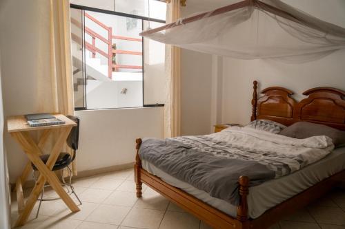 蓬塔赫尔莫萨Casa mar surfhouse的一间卧室设有天蓬床和窗户。