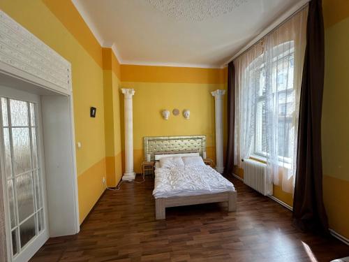 玛丽亚温泉Schloss Ambras的卧室配有一张床铺,位于一个黄色墙壁的房间