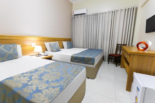 里贝朗普雷托Hotel Dan Inn Express Ribeirão Preto的酒店客房设有两张床和电视。