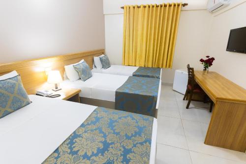 里贝朗普雷托Hotel Dan Inn Express Ribeirão Preto的酒店客房配有两张床和一张书桌