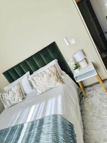 哈博罗内Unit B1 Motswedi Place的一间卧室配有一张带绿色床头板的床