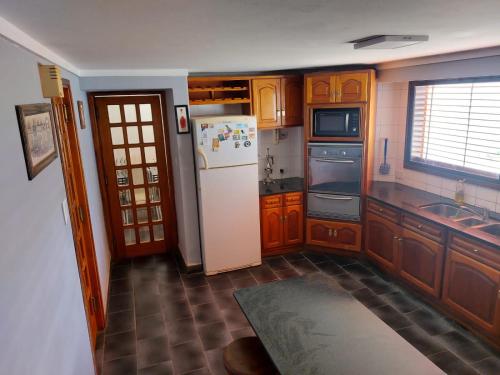 罗卡将军市Ticas的厨房配有木制橱柜和白色冰箱。