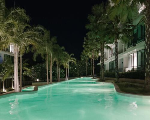 拉威海滩La Vita Phuket Rawai的夜间棕榈树游泳池
