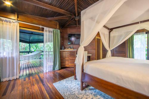 福尔图纳Chachagua Rainforest Hotel & Hot Springs的一间卧室设有天蓬床和一间浴室。