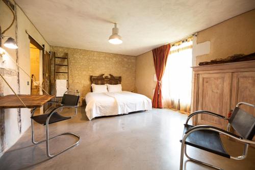 MarsacDomaine De Chantemerle B'nB的卧室配有一张床、一张桌子和椅子