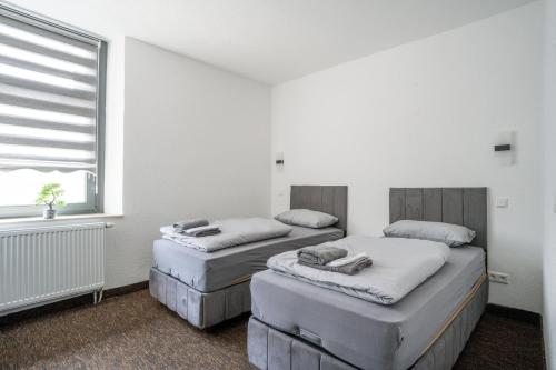 杜伊斯堡Duisburger Hostel的白色客房的两张床,设有窗户
