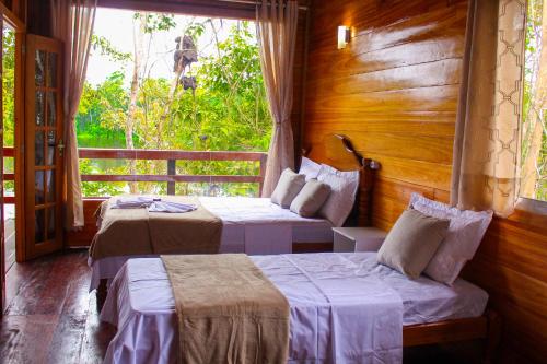 Careiro海豚酒店的带窗户的客房内的两张床