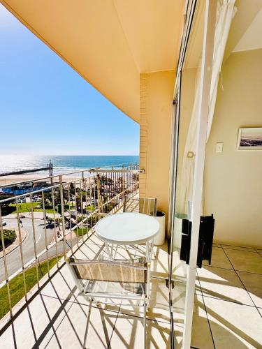 德班Nomacurvy beach front accommodation的一个带桌椅和海滩的阳台