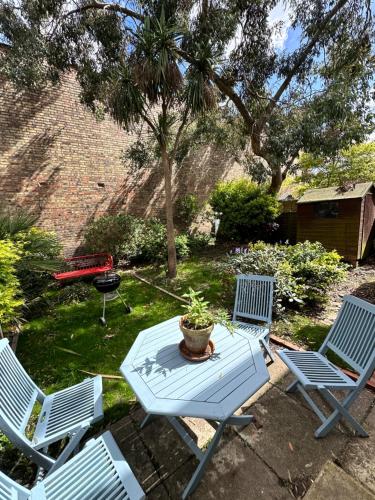 伦敦Charming, Renovated Residence in Willesden Green的庭院设有三把椅子和一张桌子及盆栽植物