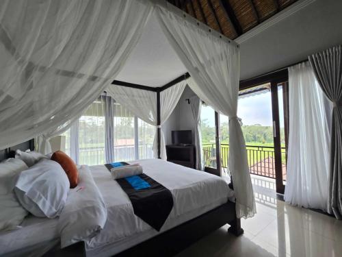 PenginyahanBelvilla 93799 Kasuari Villa Three Bedroom At Taro Village Ubud的卧室设有天蓬床和阳台