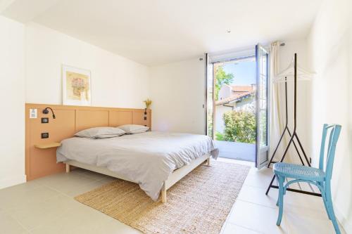 比亚里茨La Conciergerie Biarritz的一间卧室配有一张床和一张蓝色椅子