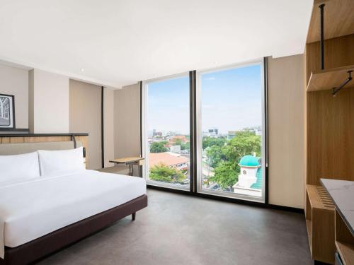 雅加达ibis Jakarta Raden Saleh的酒店客房设有一张床和一个大窗户