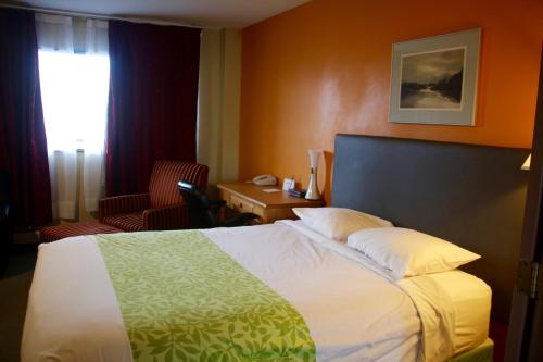 安克雷奇Americas Best Value Inn & Suites Anchorage Airport的配有一张床、一张书桌和一扇窗户的酒店客房
