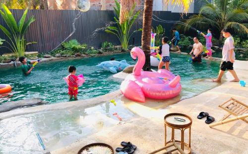 美寿Cóc Retreat Mỹ Tho City的一群儿童在游泳池玩耍