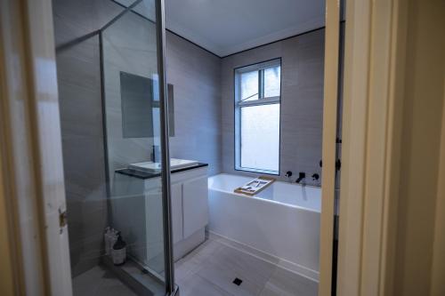 珀斯Urban Oasis Hideaway的带淋浴和浴缸的浴室以及窗户。