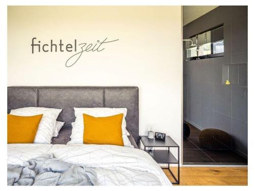 WaldershofFichtelTijd Wellness Sauna Whirlpool的卧室配有一张挂有墙上标志的床