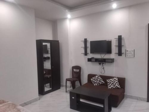 HazārībāgHotel Alakhraj Palace的客厅配有沙发和墙上的电视