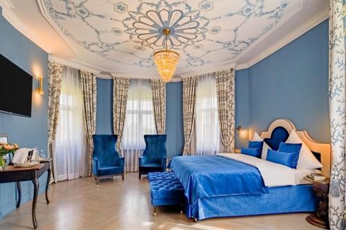 Bertsdorf阿申瑞尼兹斯加罗酒店的一间卧室设有一张床、蓝色的墙壁和吊灯。