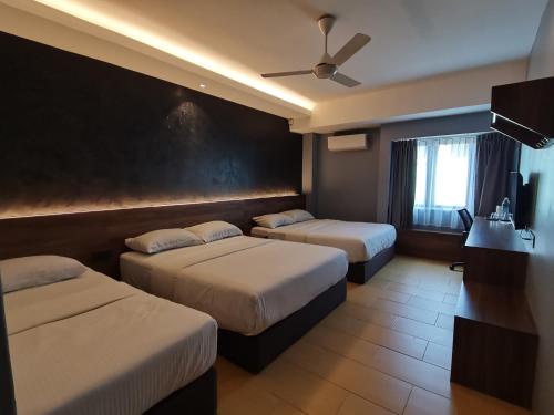 卢穆特Lumut Hotel的酒店客房配有两张床和吊扇。