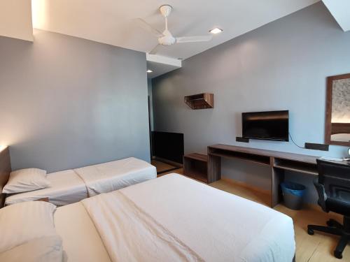 卢穆特Lumut Hotel的客房设有两张床和一张书桌及一台电视。