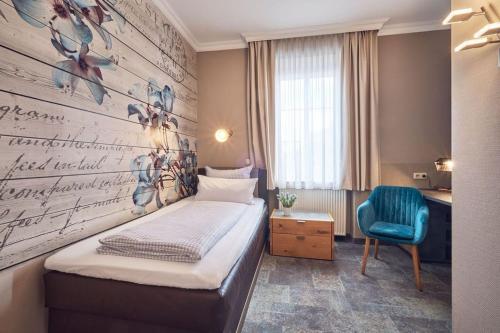 施塔恩贝格斯塔尔恩贝尔格希酒店的小房间设有一张床和一张蓝色椅子