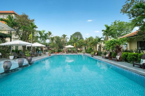 宁平Dong Ne Tam Coc Hotel & Resort的度假村的游泳池,配有椅子和遮阳伞