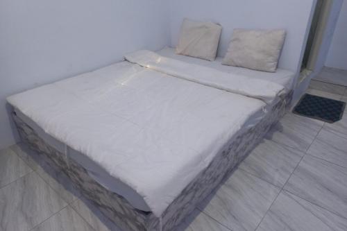 直葛OYO 93900 Guest House Cinta Damai的配有白色床单和枕头的宿舍间内的一张床位