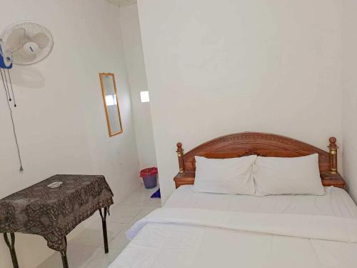 KotabumiOYO 93902 Guest House Pahlawan Syariah的一间卧室配有一张床、一张桌子和风扇