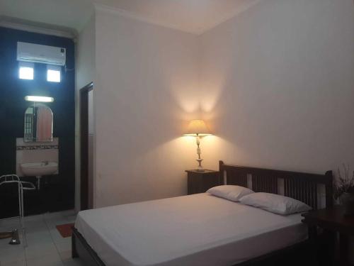 斯勒曼Capital O 93938 Wisma Pamungkas Syariah的卧室配有一张床和墙上的灯。