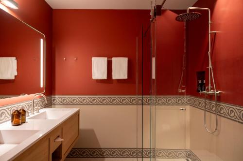 切勒里纳Cresta Palace Celerina的浴室设有红色的墙壁、淋浴和水槽