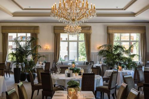 切勒里纳Cresta Palace Celerina的一间带桌椅和吊灯的用餐室