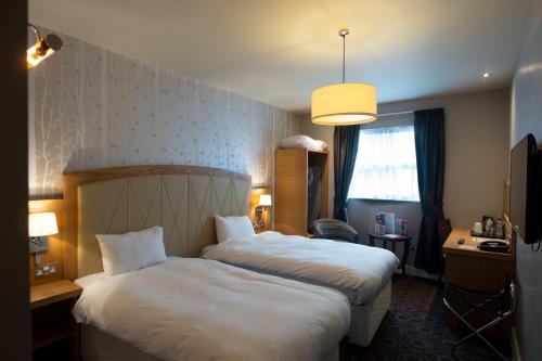 亨廷登桑福德豪斯威瑟斯本酒店的酒店客房设有两张床和窗户。