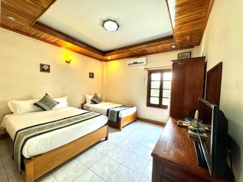 琅勃拉邦Heuang Paseuth Hotel 香帕赛酒店的一间卧室配有两张床和电视。