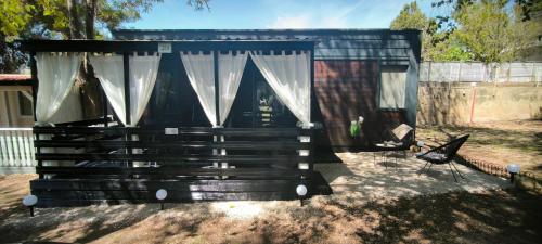 沃迪切Mobile home Ivan Vodice的院子里的黑色棚子,带窗帘和椅子