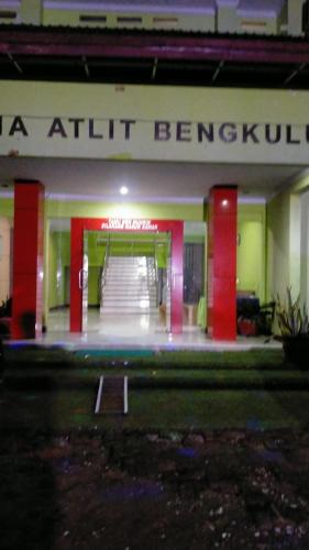明古鲁省Hotel Grand Atlet Bengkulu的红色柱子和楼梯栏杆的建筑物入口