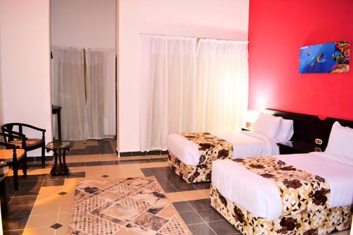 Abū GhuşūnHostmark Zabargad Beach Resort的酒店客房设有两张床和红色的墙壁。