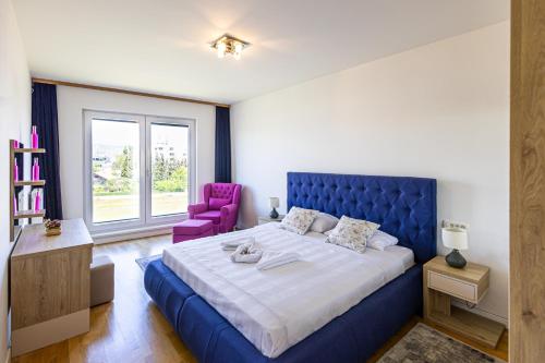 萨拉热窝Ilidza River Apartments的一间卧室配有蓝色的床和紫色椅子