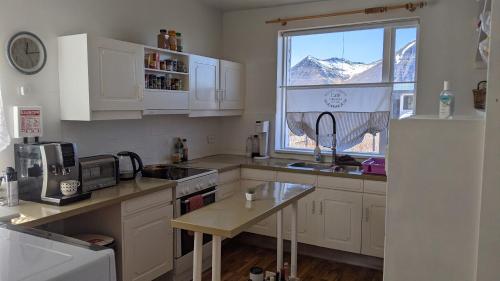 FlateyriFlateyri guesthouse的厨房配有白色橱柜和山景窗户。