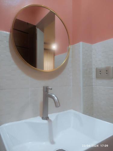 LocsinCasita de Reina Staycation House - A cozy 1-Bedroom condo-style house的浴室水槽和上面的圆镜子