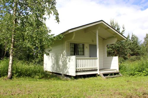 萨翁林纳Vuohimäki Camping Savonlinna的一座白色的小房子,在田野上设有门廊