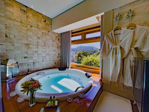 蒙特韦尔迪Hotel Harmonia Monte Verde的一间带大浴缸和窗户的浴室