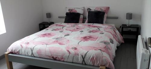 塞尔方丹Au Chant Des Roches - Cerfontaine的一间卧室配有一张带粉红色花卉床罩的床。