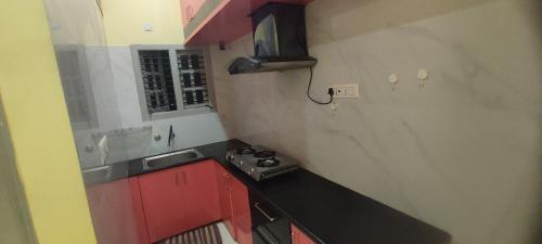 迈索尔ADH Amilia Residency的一个带水槽和红色橱柜的小厨房