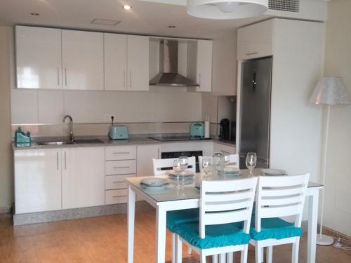 阿桂拉斯Apartamento céntrico cerca de la playa的厨房配有白色橱柜和桌椅