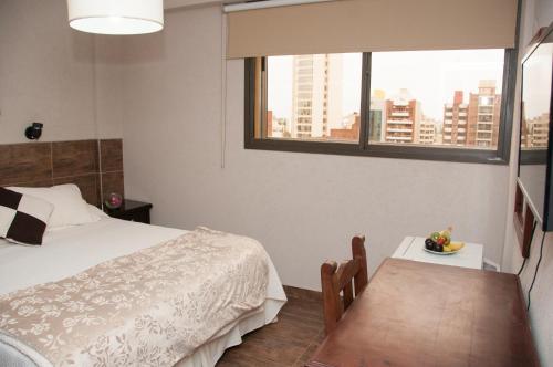 拉普拉塔Hotel del Rey的一间卧室配有一张床、一张桌子和一个窗户。