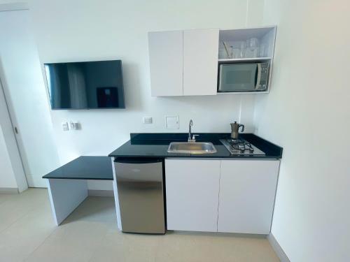 蒙特里亚Apartaestudio Brumilo 3的白色的厨房配有水槽和微波炉