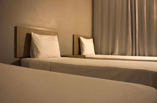 阿拉瓜伊纳Hotel Ipanema的酒店的客房内设有两张带白色枕头的床。